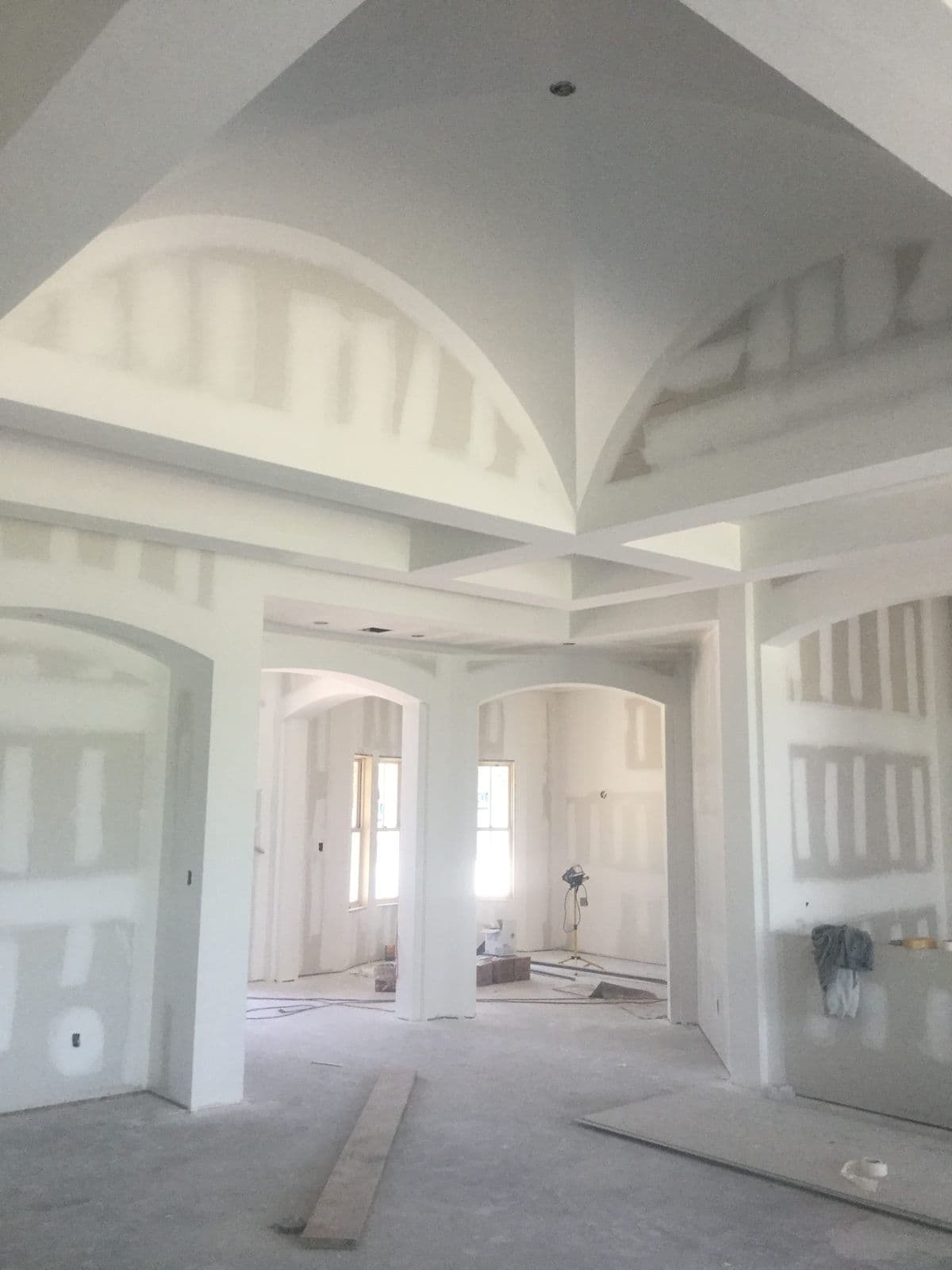 Smooth finished drywall arches, columns and a vaulted ceiling in a large open room under construction